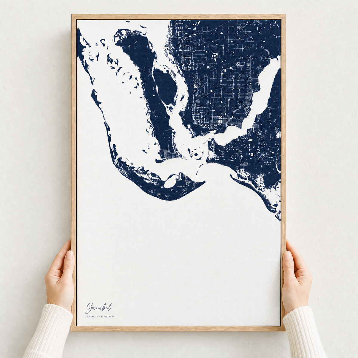 Sanibel canvas map — hands holding the canvas in an oak frame