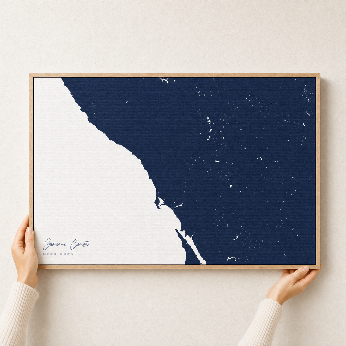 Sonoma Coast canvas map — hands holding the canvas in an oak frame