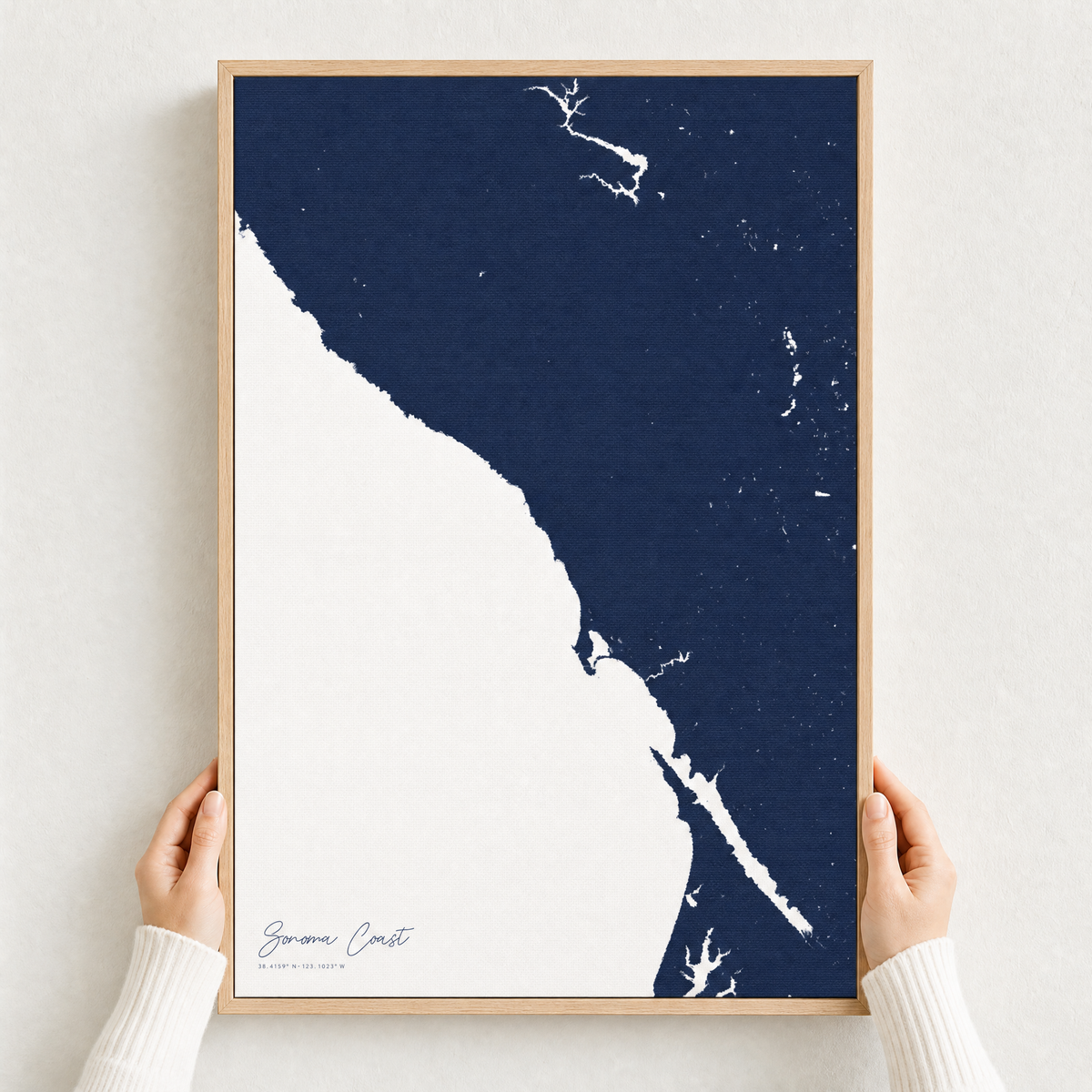 Sonoma Coast canvas map — hands holding the canvas in an oak frame