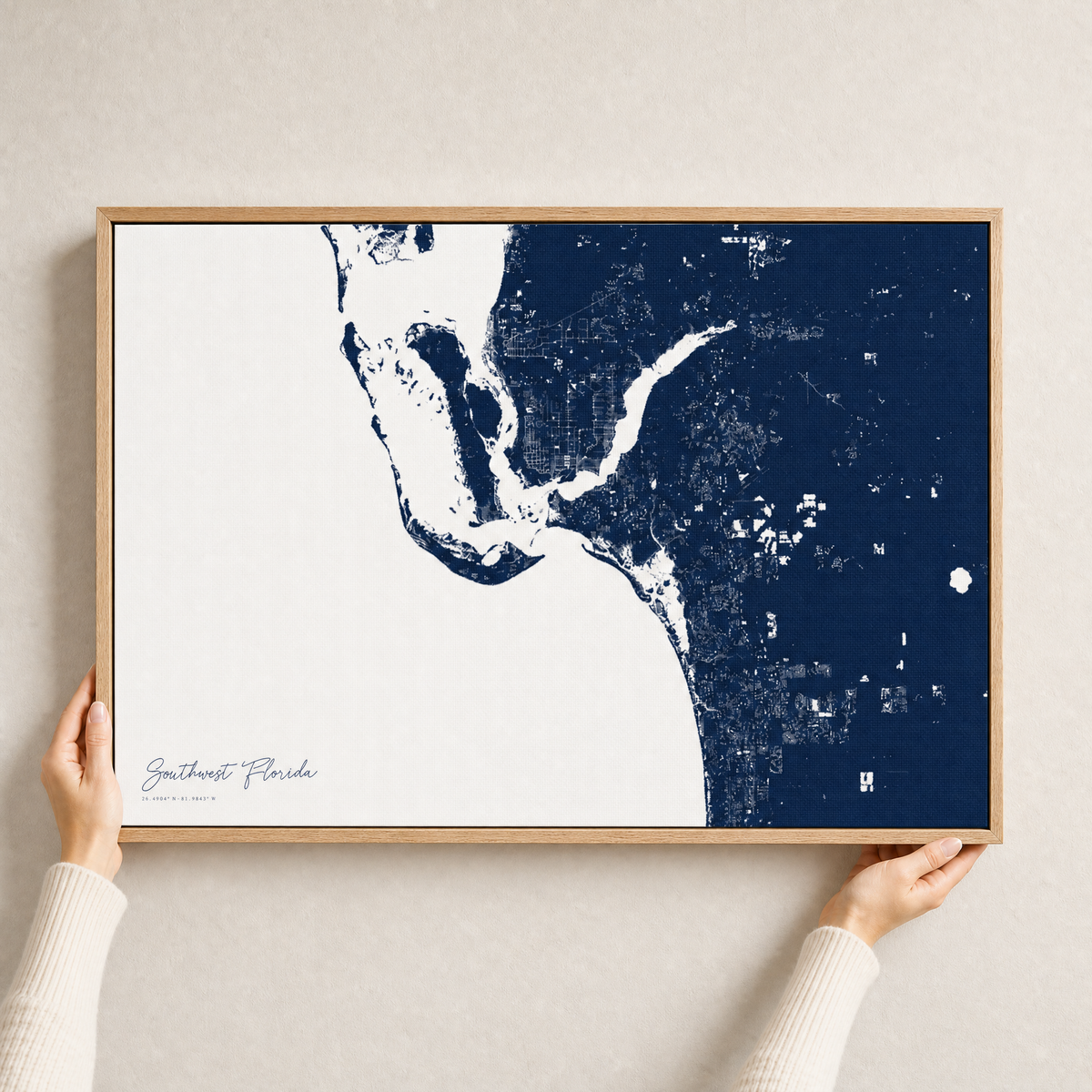 Southwest Florida canvas map — hands holding the canvas in an oak frame