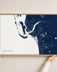 Southwest Florida canvas map — hands holding the canvas in an oak frame