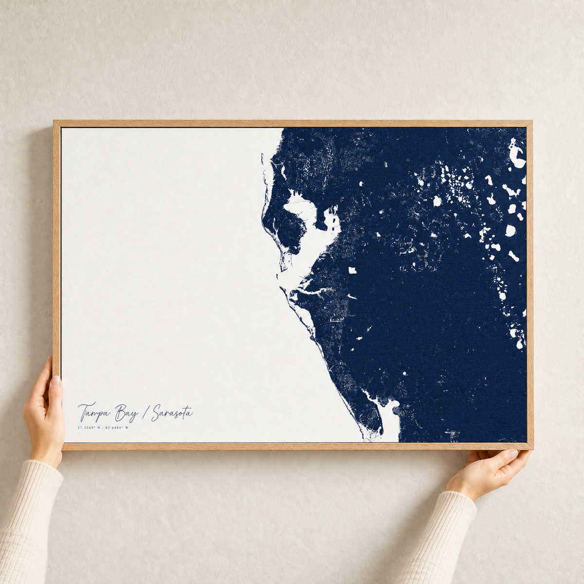 Tampa Bay / Sarasota canvas map — hands holding the canvas in an oak frame