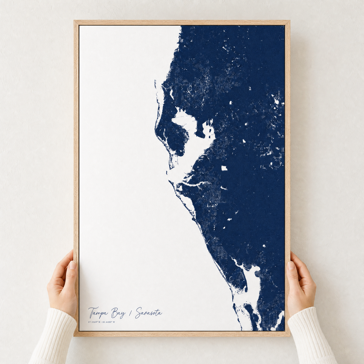 Tampa Bay / Sarasota canvas map — hands holding the canvas in an oak frame