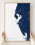 Tampa Bay / Sarasota canvas map — hands holding the canvas in an oak frame