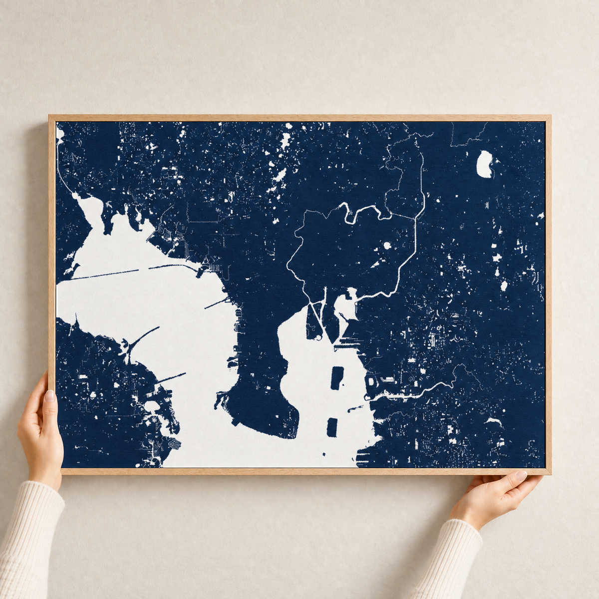 Tampa canvas map — hands holding the canvas in an oak frame