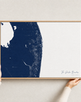 The Palm Beaches canvas map — hands holding the canvas in an oak frame