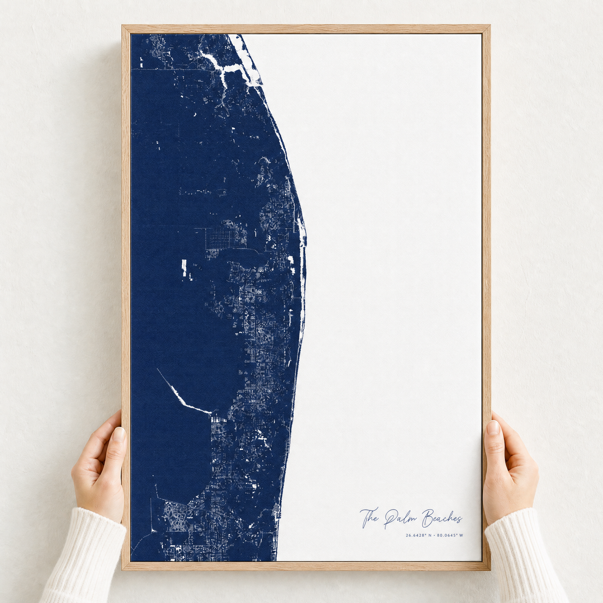 The Palm Beaches canvas map — hands holding the canvas in an oak frame