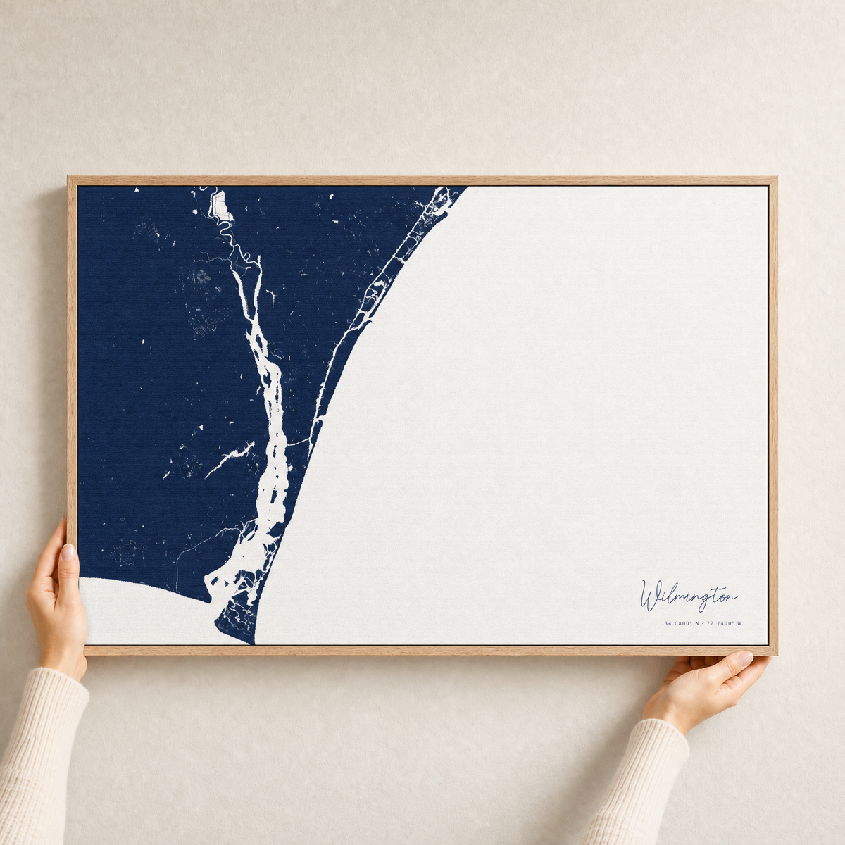 Wilmington canvas map — hands holding the canvas in an oak frame